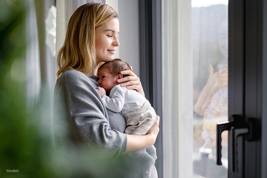 Young blonde mother holds her newborn baby.